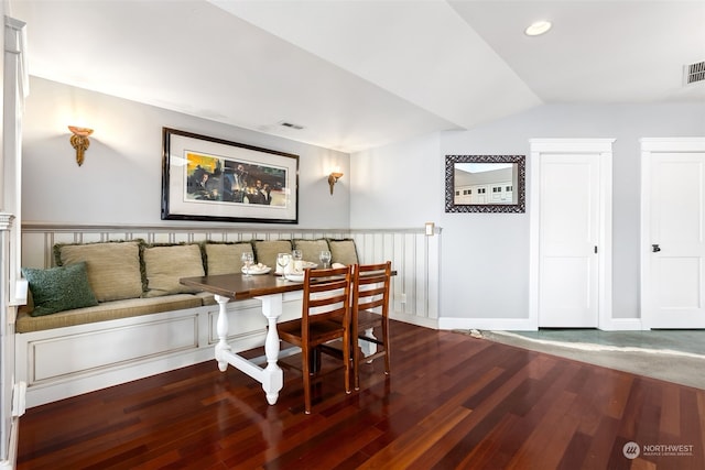 dining area featuring breakfast area, dark wood-type flooring, and vaulted ceiling