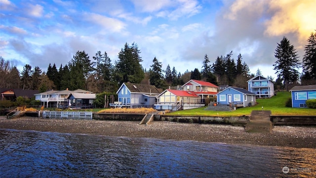 rear view of house featuring a water view and a lawn