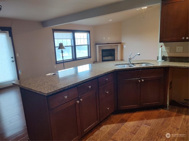 kitchen featuring kitchen peninsula, dark hardwood / wood-style flooring, light stone counters, and sink