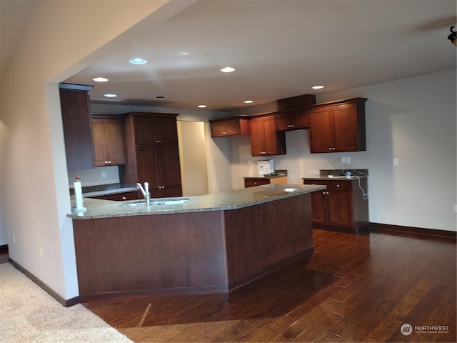 kitchen featuring kitchen peninsula, sink, dark hardwood / wood-style floors, and stone countertops