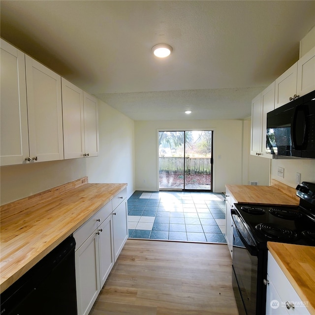 kitchen featuring black appliances, wood counters, white cabinetry, and light hardwood / wood-style flooring