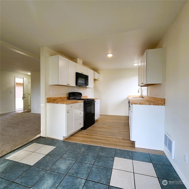 kitchen with light hardwood / wood-style flooring, white cabinets, black appliances, and sink