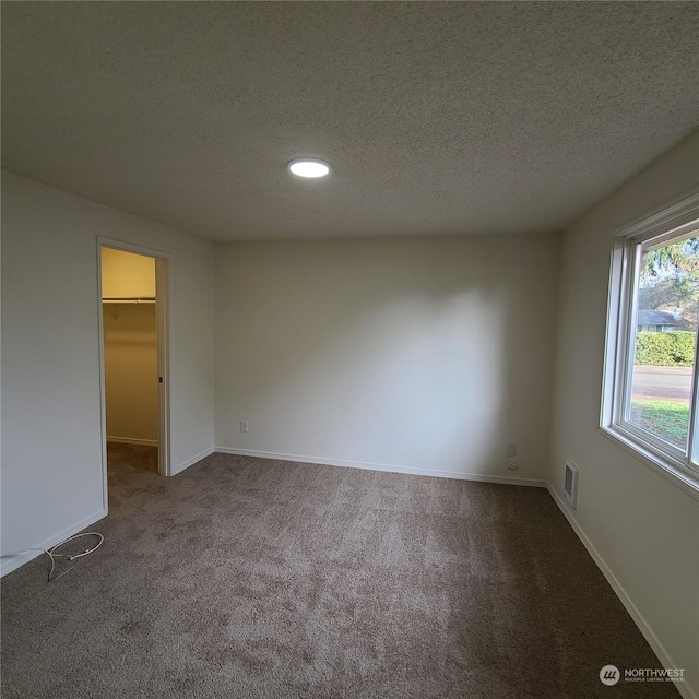 empty room featuring carpet and a textured ceiling