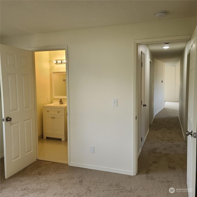 hall featuring a textured ceiling and light carpet