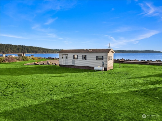 back of property with a lawn and a water view