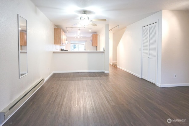 unfurnished living room with a baseboard heating unit, track lighting, ceiling fan, and dark wood-type flooring