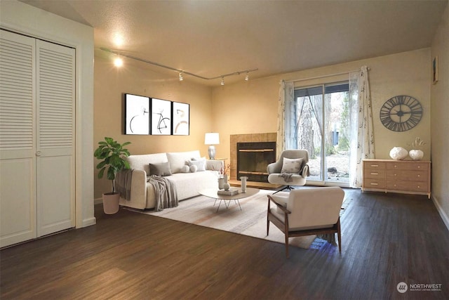 living room featuring a tile fireplace, dark hardwood / wood-style floors, and track lighting