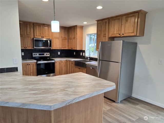 kitchen with backsplash, sink, appliances with stainless steel finishes, light hardwood / wood-style floors, and kitchen peninsula