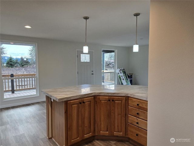 kitchen with kitchen peninsula, plenty of natural light, pendant lighting, and dark hardwood / wood-style floors