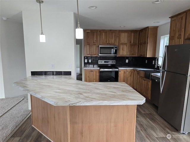 kitchen with kitchen peninsula, dark hardwood / wood-style flooring, tasteful backsplash, stainless steel appliances, and hanging light fixtures