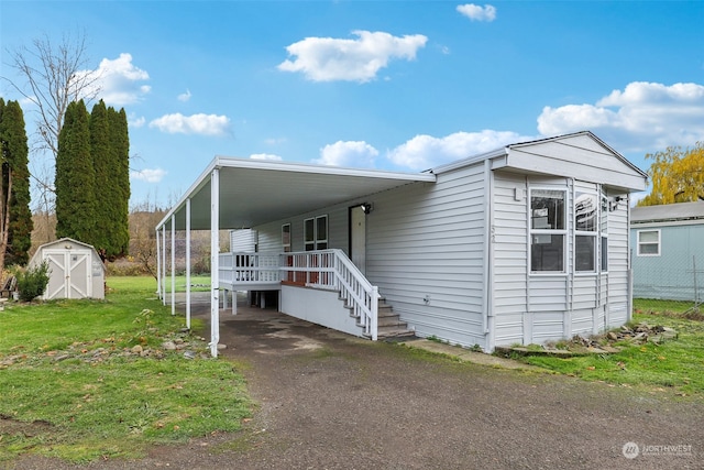 manufactured / mobile home featuring a front lawn, a carport, and a storage unit