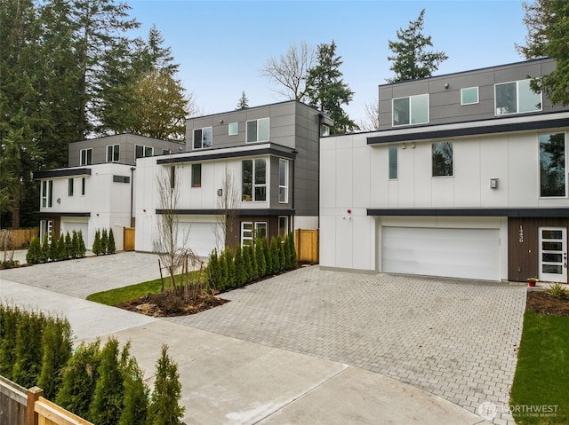 contemporary home with an attached garage, decorative driveway, and board and batten siding