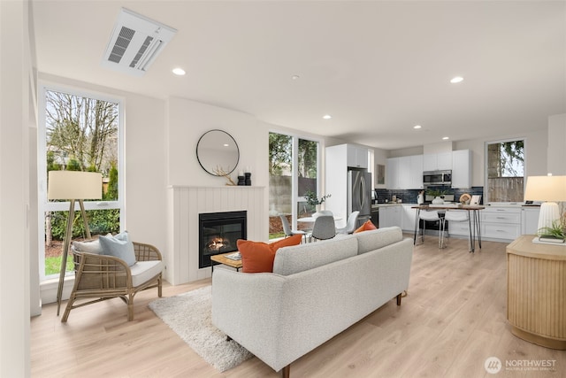 living area with visible vents, a healthy amount of sunlight, and light wood finished floors