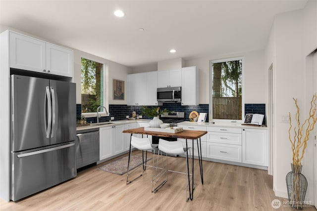 kitchen featuring a sink, decorative backsplash, appliances with stainless steel finishes, and white cabinets