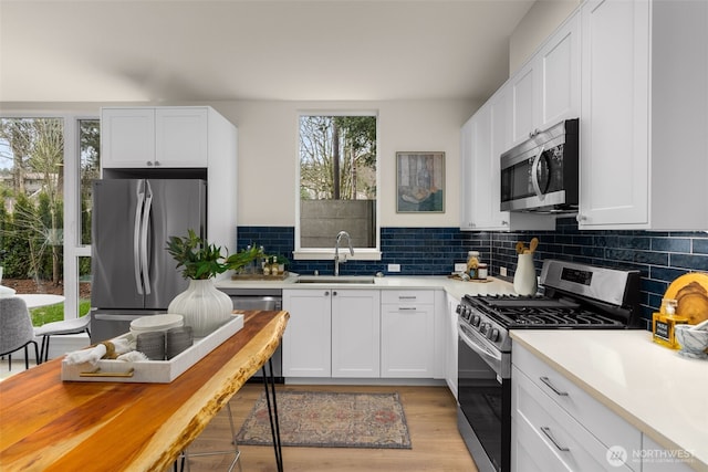 kitchen with decorative backsplash, white cabinets, appliances with stainless steel finishes, and a sink