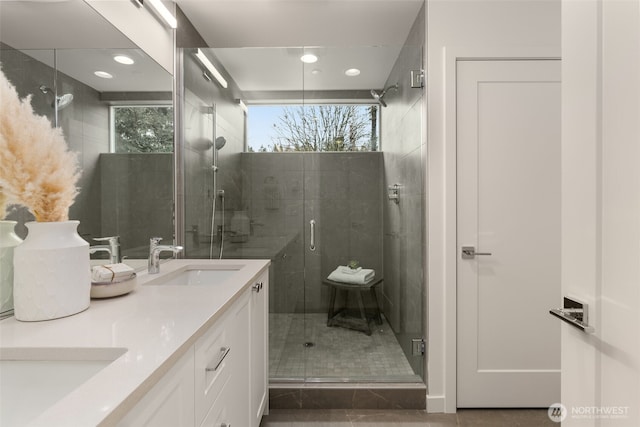 full bath with a sink, recessed lighting, a shower stall, tile patterned flooring, and double vanity