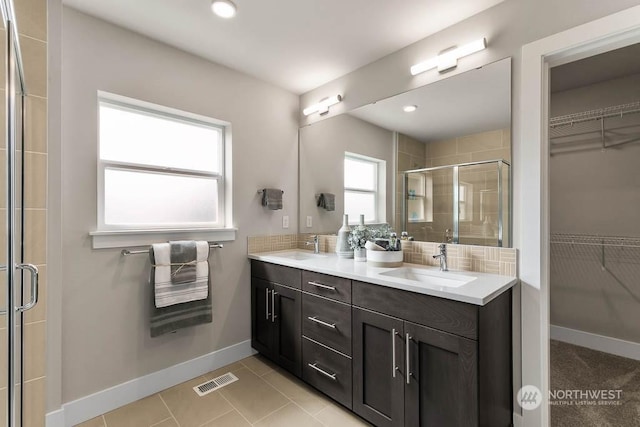 bathroom with tile patterned flooring, vanity, and walk in shower