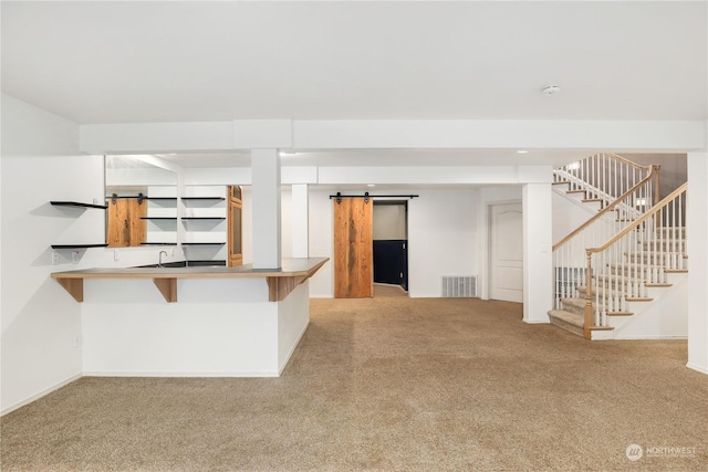 kitchen featuring a barn door, kitchen peninsula, and light carpet