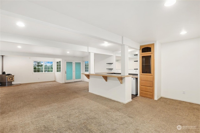 kitchen with light carpet, beam ceiling, a kitchen breakfast bar, and dishwashing machine