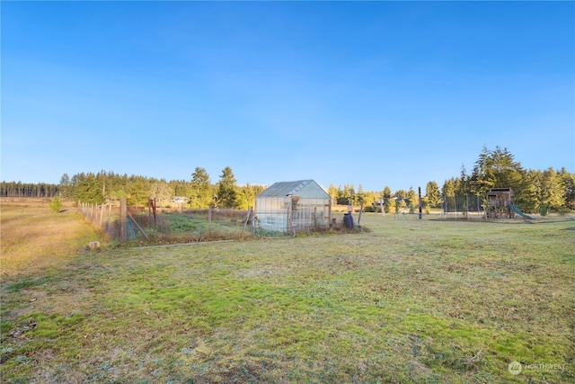 view of yard featuring a rural view, an outdoor structure, and a playground