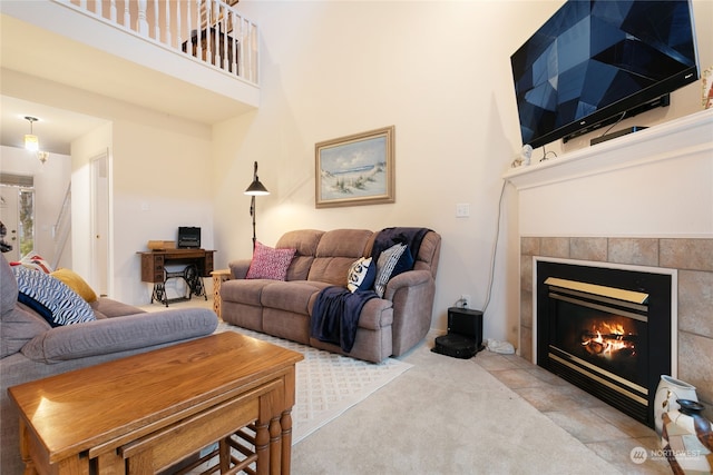 carpeted living room with a tiled fireplace and a towering ceiling