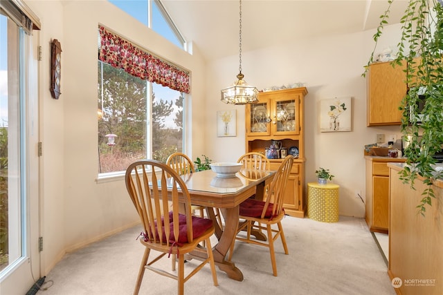 carpeted dining room with a chandelier and vaulted ceiling