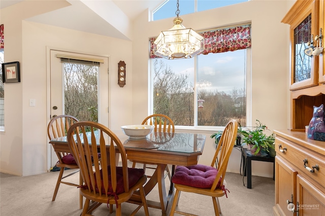 dining room with light colored carpet, lofted ceiling, and a notable chandelier