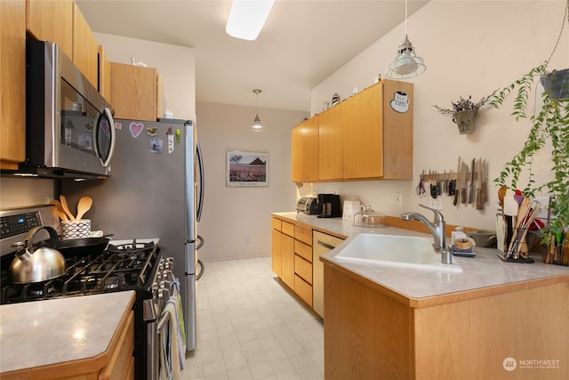 kitchen featuring kitchen peninsula, pendant lighting, stainless steel appliances, and sink