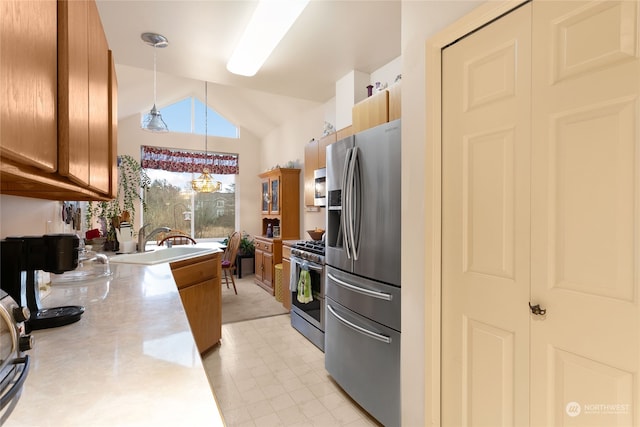 kitchen featuring sink, a notable chandelier, lofted ceiling, decorative light fixtures, and appliances with stainless steel finishes