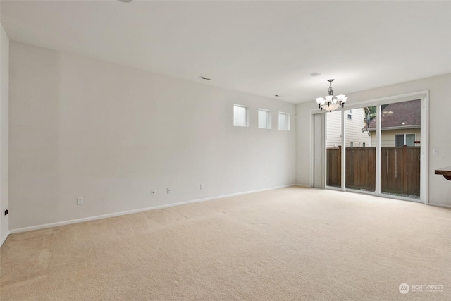 empty room featuring light carpet and a chandelier