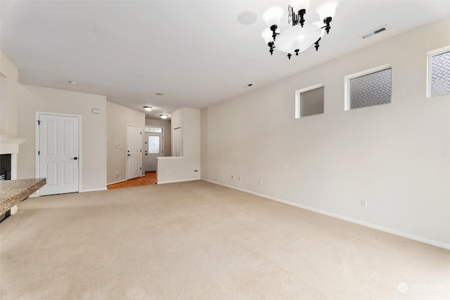 unfurnished living room with light colored carpet and an inviting chandelier