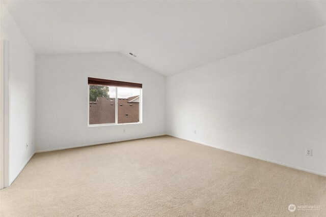 carpeted spare room with lofted ceiling