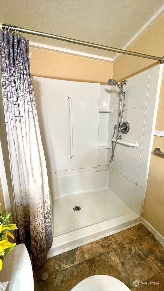 bathroom featuring toilet, curtained shower, and ornamental molding