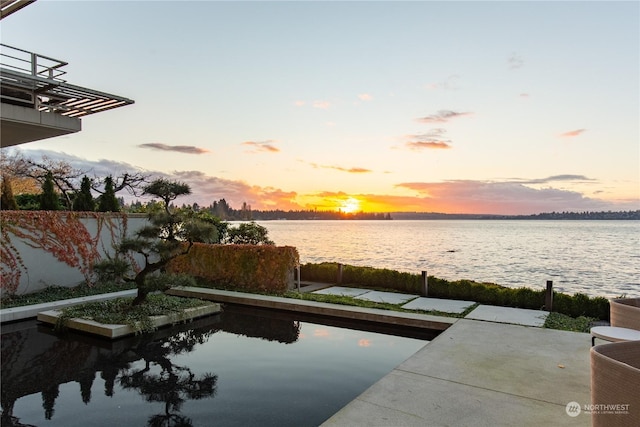 pool at dusk featuring a water view