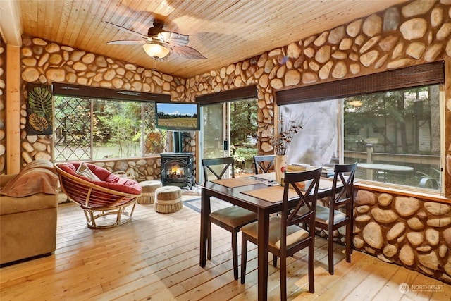 sunroom / solarium with ceiling fan, a wood stove, and wooden ceiling