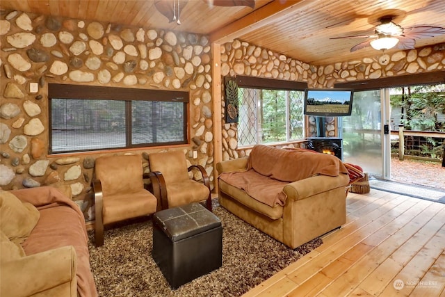 living room with wooden ceiling, a wood stove, lofted ceiling with beams, hardwood / wood-style flooring, and ceiling fan