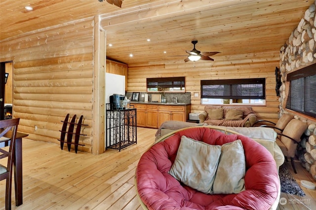 living room featuring ceiling fan, light wood-type flooring, rustic walls, and wood ceiling