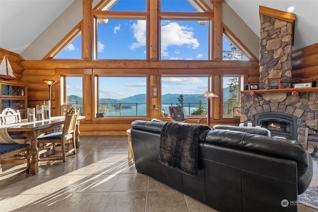 living room featuring a fireplace, high vaulted ceiling, rustic walls, and a healthy amount of sunlight