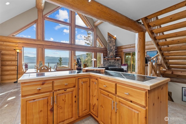 kitchen with high vaulted ceiling, a mountain view, a stone fireplace, and log walls