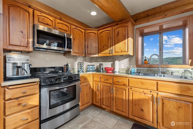 kitchen with beam ceiling, sink, light tile patterned floors, and stainless steel appliances