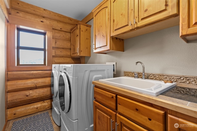 clothes washing area featuring wood walls, cabinets, separate washer and dryer, and sink