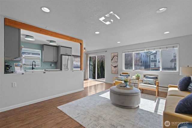 living area with a wealth of natural light, a textured ceiling, recessed lighting, and wood finished floors