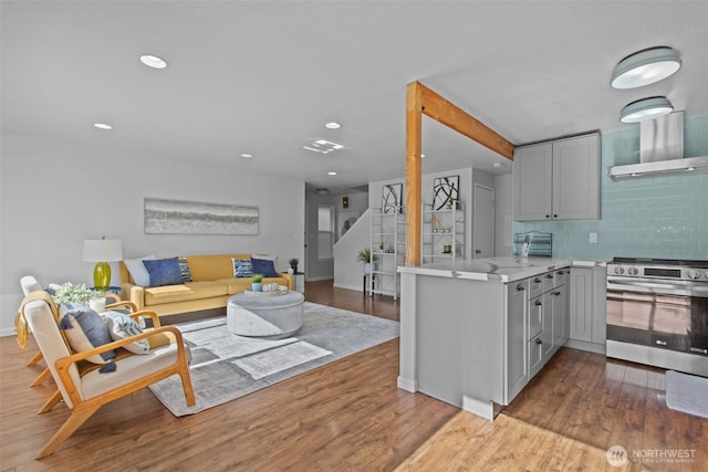 kitchen with light countertops, stainless steel electric range oven, backsplash, and wood finished floors