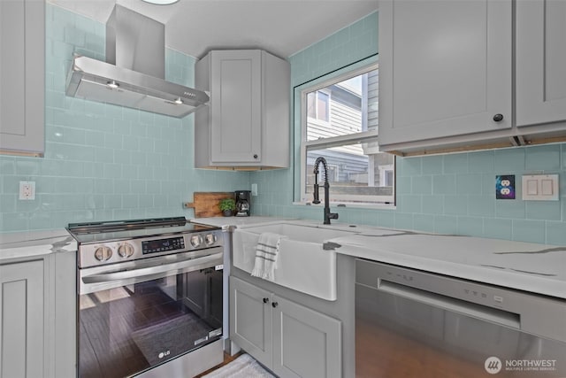 kitchen with stainless steel appliances, backsplash, a sink, and wall chimney range hood