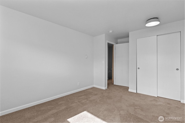 unfurnished bedroom with a closet, carpet flooring, and baseboards