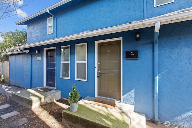 property entrance featuring a porch and stucco siding