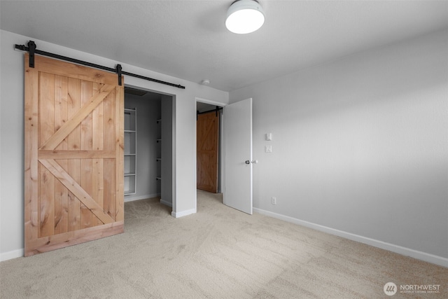 1128 N 91st St, Seattle, WA 98103 - unfurnished bedroom featuring light colored carpet, baseboards, a barn door, a walk in closet, and a closet