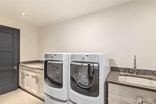 clothes washing area featuring washer and clothes dryer, sink, and cabinets