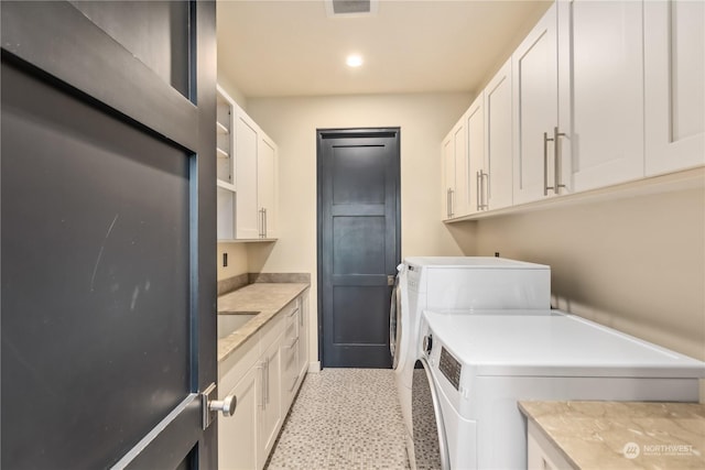 laundry area featuring cabinets, light tile patterned floors, and washer and clothes dryer