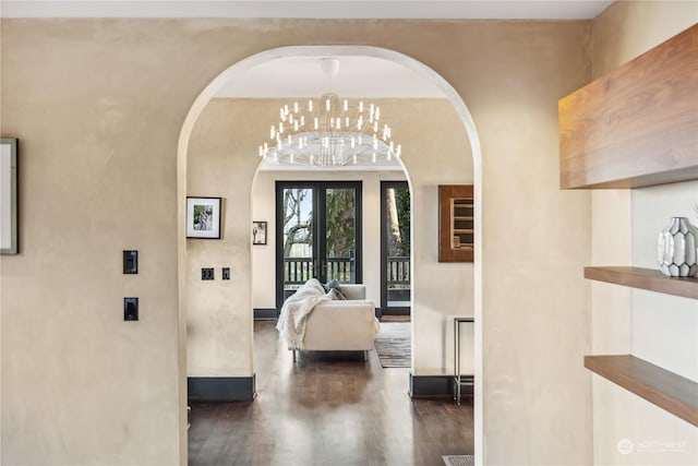 unfurnished bedroom featuring access to outside, french doors, dark wood-type flooring, and a notable chandelier